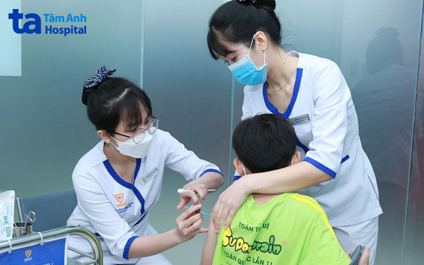 Điều dưỡng viên trấn an trẻ trước khi tiêm vắc xin