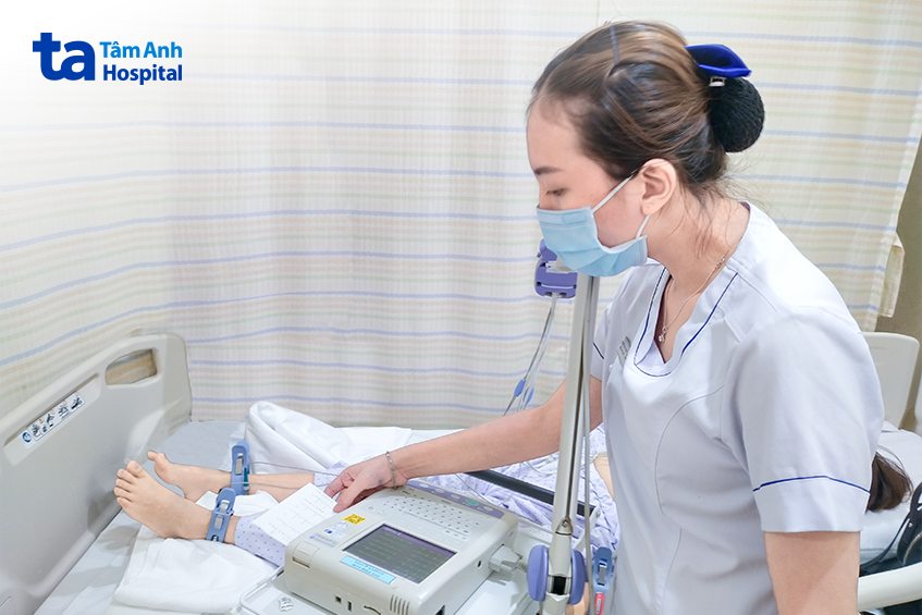 Điều dưỡng đang đo điện tim cho người bệnh