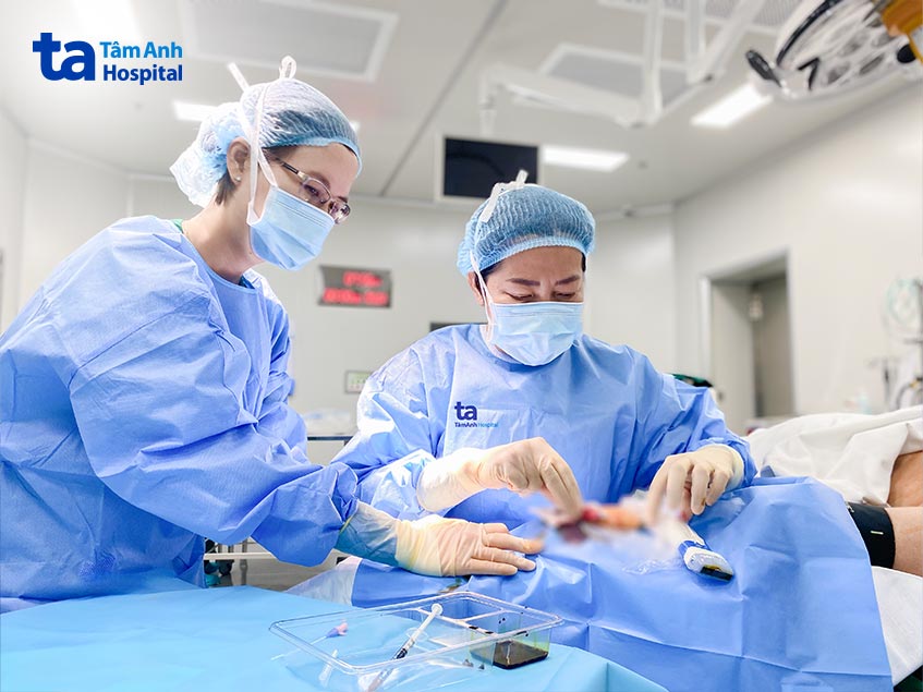 Bác sĩ Hồ Thị Xuân Nga (bên phải) đặt catheter động mạch xâm lấn dưới hướng dẫn siêu âm cho người bệnh