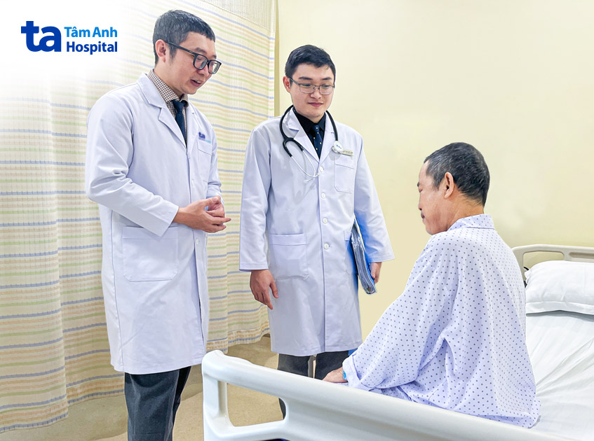 Bác sĩ Minh (trái) và bác sĩ Thiện hỏi thăm sức khỏe bệnh nhân sau can thiệp