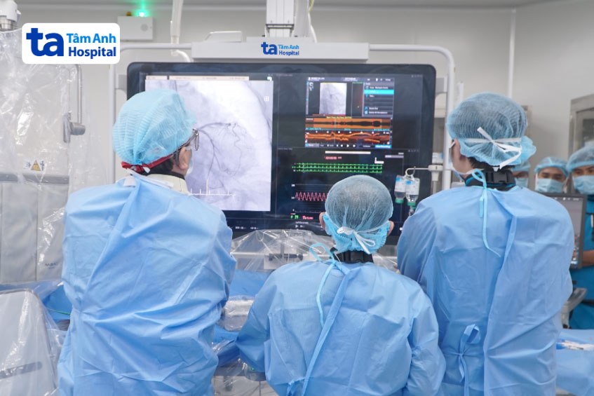 Giáo sư Nhân (bên trái) cùng ê kíp đặt stent nong mạch vành cho bà Mận với sự hỗ trợ của máy chụp cắt lớp kết quang nội mạch