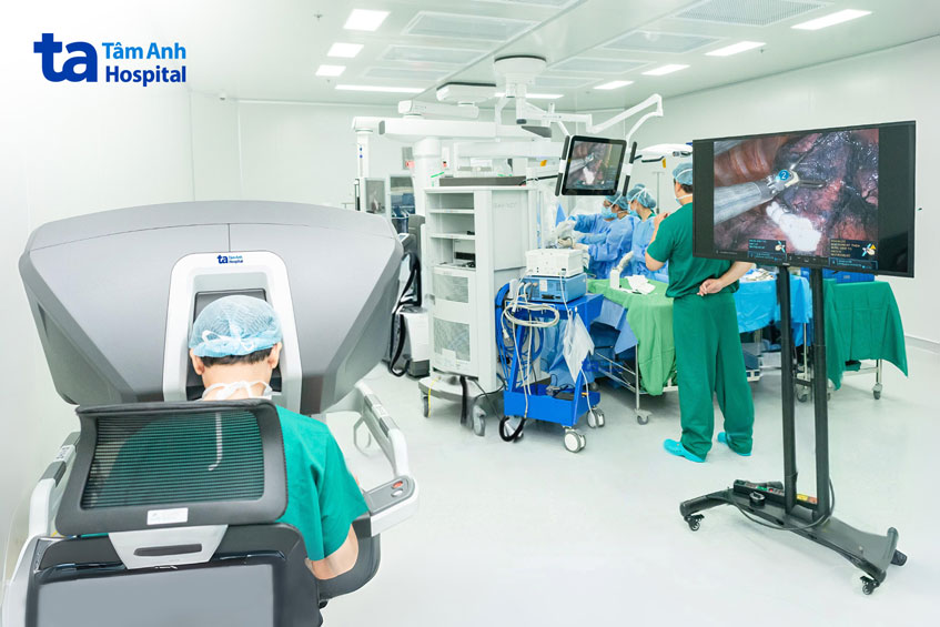 Bác sĩ Quyền ngồi ở buồng điều khiển chính, điều khiển bốn cánh tay robot thao tác cắt khối u, phối hợp nhịp nhàng cùng bác sĩ phụ mổ
