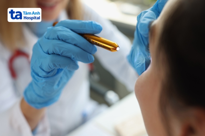 bác sĩ chiếu đèn vào từng mắt để kiểm tra phản xạ