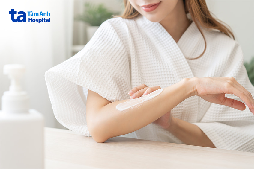 Phụ nữ đang thoa kem dưỡng làm dịu da khi bị kích ứng hoặc nổi mẩn