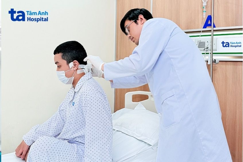 Bác sĩ kiểm tra vết thương sau phẫu thuật cho Minh.