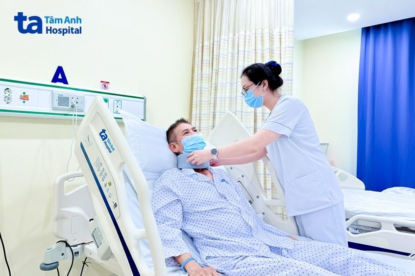 Điều dưỡng điều chỉnh nẹp cổ cho ông Viễn sau phẫu thuật.