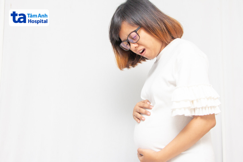 Phụ nữ mang thai ôm bụng, biểu cảm khó chịu có thể do vấn đề tiêu hóa