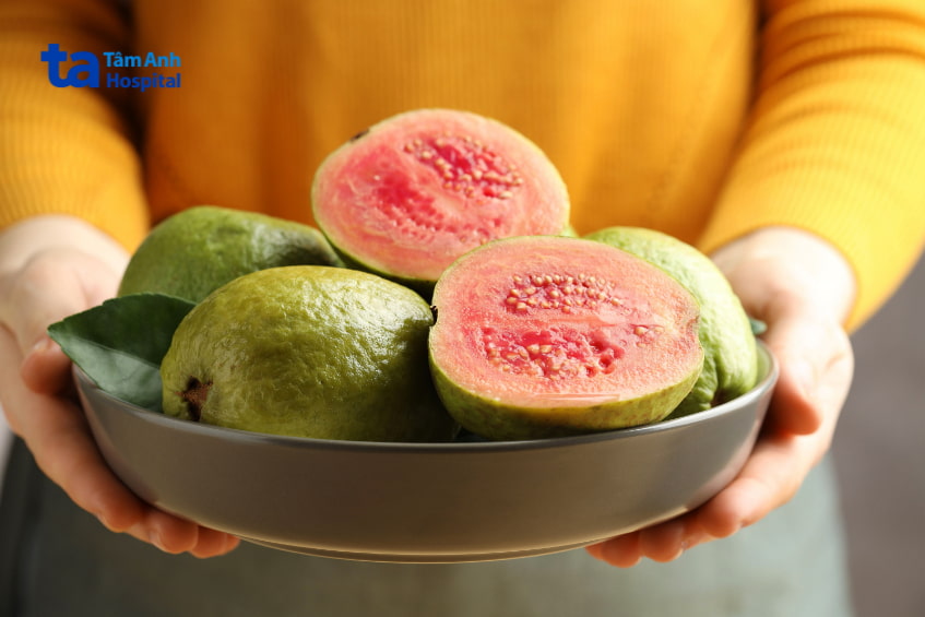 Bát ổi hồng đào tươi ngon được cầm trên tay, giàu vitamin C tốt cho bà bầu
