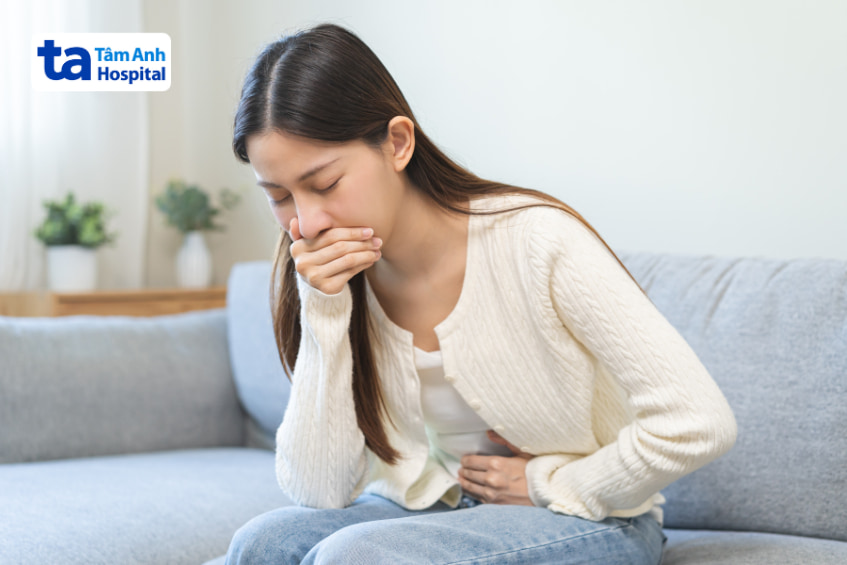 Phụ nữ ôm bụng và buồn nôn, biểu hiện triệu chứng rối loạn tiêu hóa hoặc trào ngược.