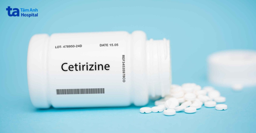 Lọ thuốc cetirizine màu trắng cùng nhiều viên nén rải ra nền xanh
