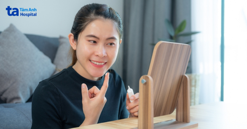 Người phụ nữ bôi kem trị mụn có chứa tretinoin trước gương trong quy trình skincare