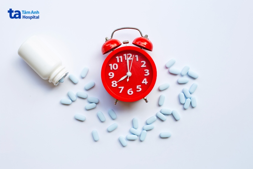 Đồng hồ đỏ cạnh viên thuốc xanh biểu thị thời gian uống Tenofovir đúng giờ