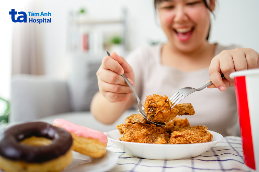 Người phụ nữ đang ăn gà rán và đồ ngọt, không phù hợp với chế độ ăn cho người trĩ