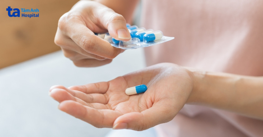 Người đang cầm viên nang kẽm màu xanh trắng trên tay, chuẩn bị uống thực phẩm bổ sung kẽm.