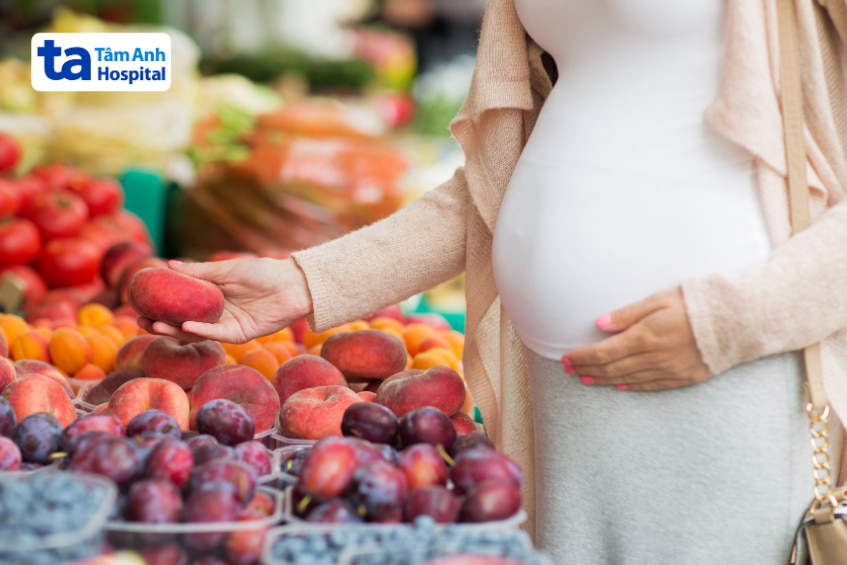 Mẹ bầu chọn đào tươi tại chợ, một loại trái cây tốt trong chế độ ăn thai kỳ