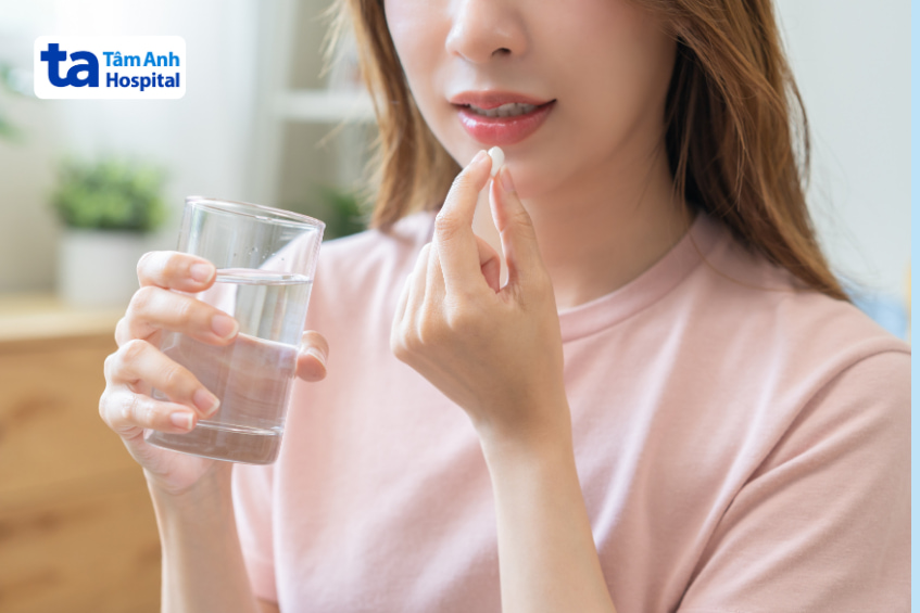 Phụ nữ uống thuốc với nước, minh họa cách dùng thuốc fenofibrate an toàn