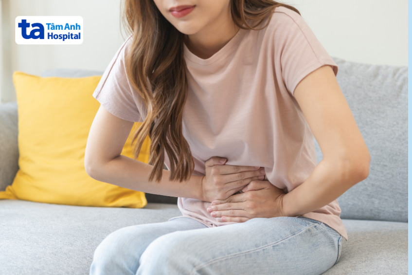 Người phụ nữ ôm bụng đau, có thể là tác dụng phụ của thuốc hạ cholesterol Ezetimibe