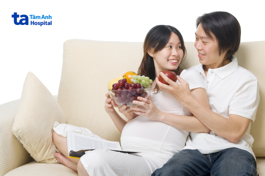 Vợ chồng cùng thưởng thức trái cây, người chồng đưa táo cho vợ bầu