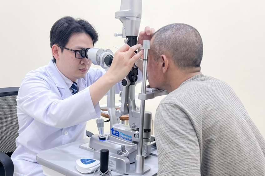 bác sĩ huy nhìn qua đèn khe, dùng que bông vô trùng lấy dị vật ra khỏi mắt anh phong