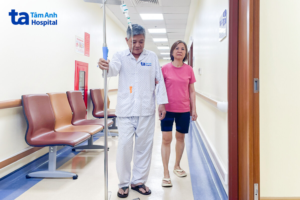 người bệnh cùng vợ tập di chuyển ngoài hành lang