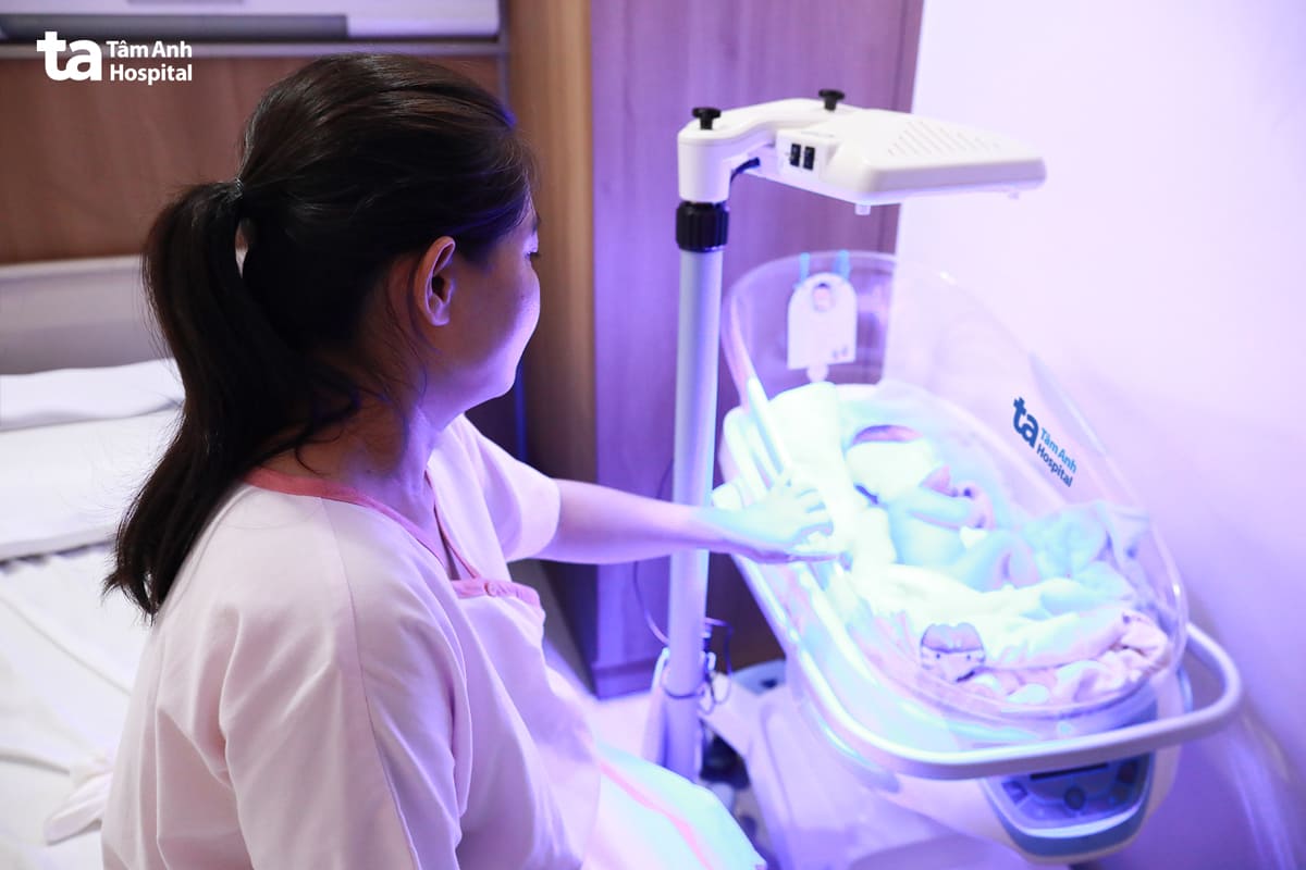 chị chăm sóc con đang chiếu đèn điều trị vàng da sơ sinh