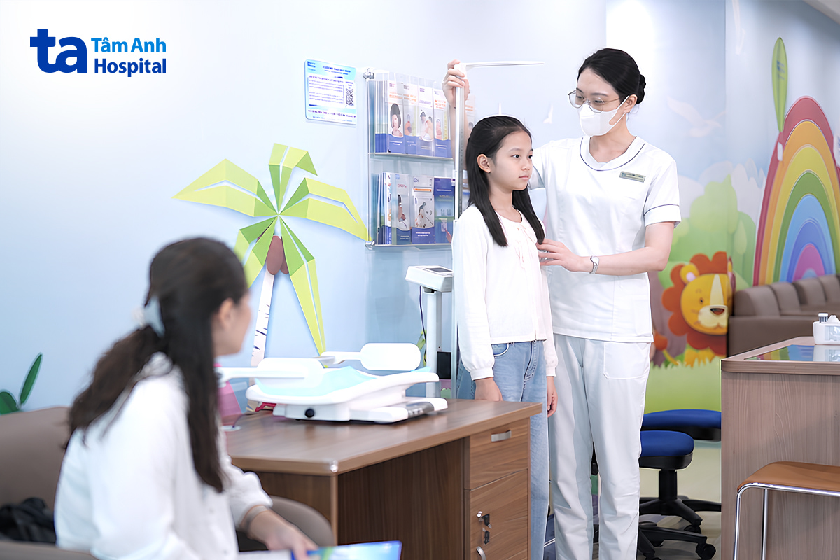 Nhân viên y tế đo chiều cao cho bé gái khi thăm khám.