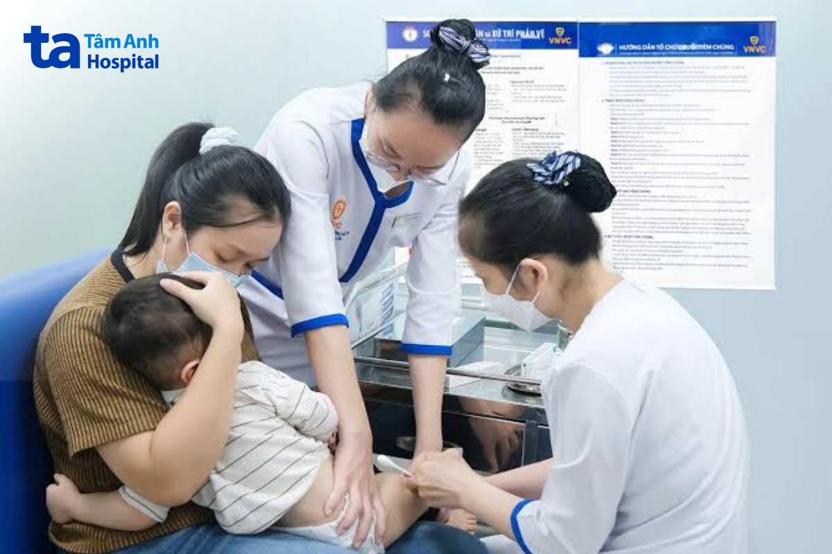 mẹ ẵm em bé tiêm vắc xin