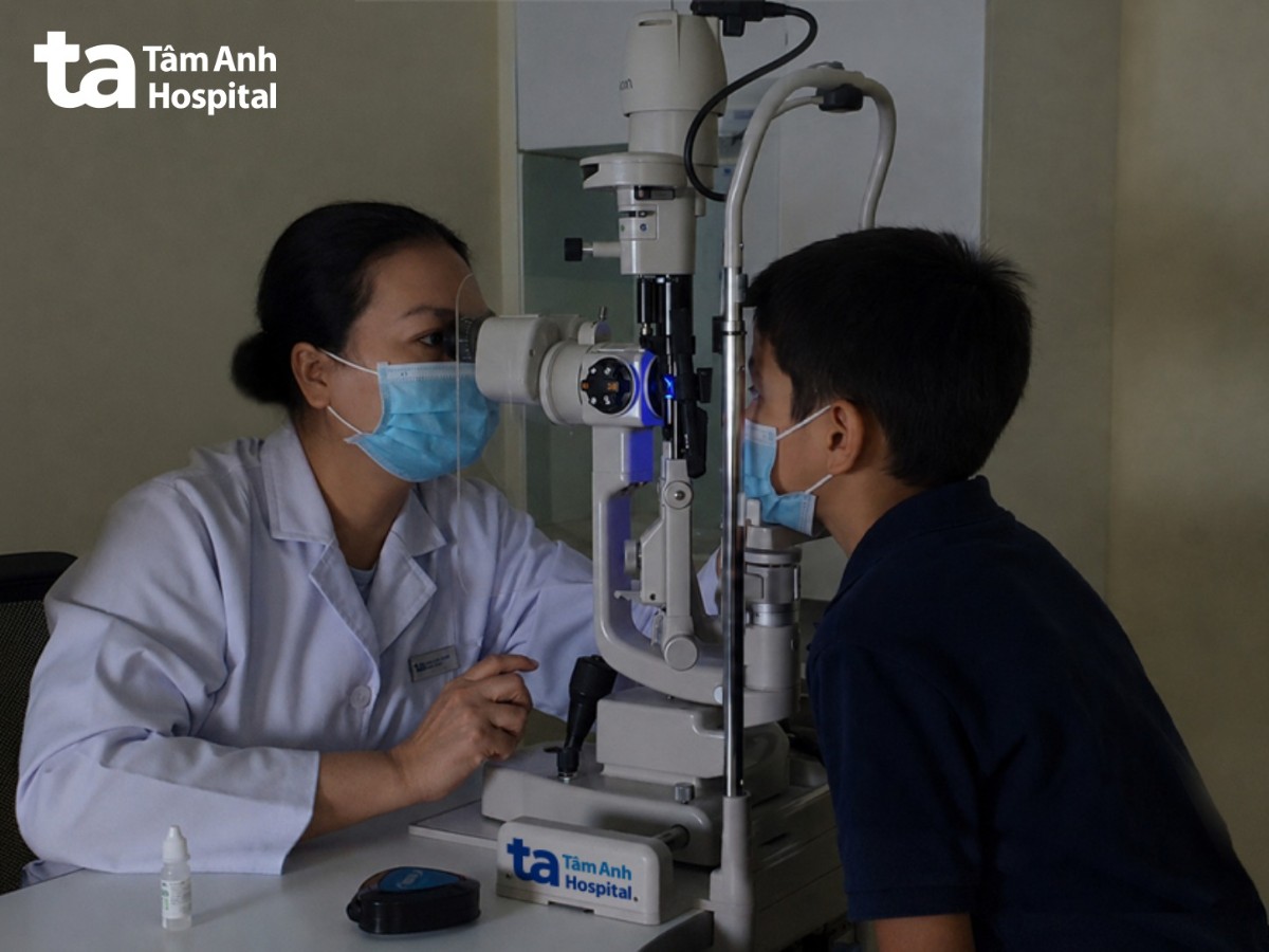 bác sĩ tắt đèn, soi ánh sáng xanh để kiểm tra bề mặt giác mạc của bé