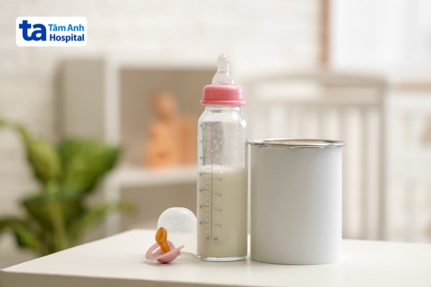 Bình sữa công thức và hộp sữa bột đặt trên bàn trong phòng của trẻ