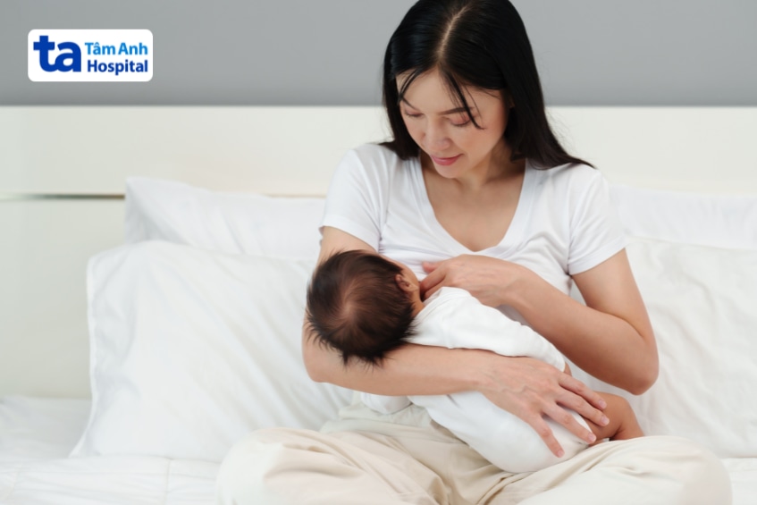 Mẹ ôm cho trẻ bú sữa mẹ trên giường khi trẻ bị viêm ruột
