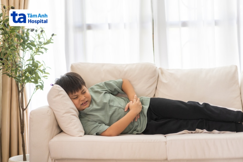 Trẻ nằm ôm bụng vì cơn đau do bệnh Crohn