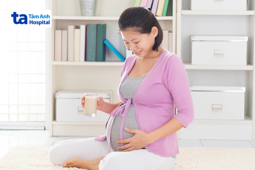 Mẹ bầu cầm ly sữa đậu nành trong nhà.
