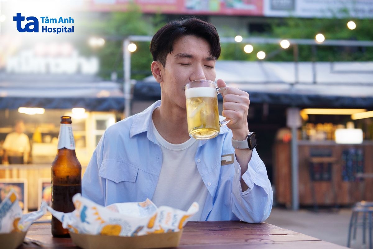 Người đàn ông đang uống bia tại bàn ăn