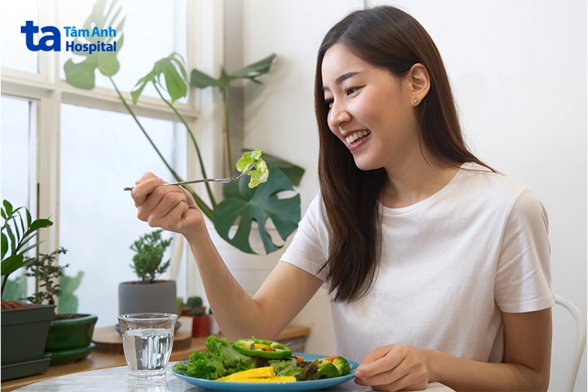Người phụ nữ thưởng thức bữa ăn với nhiều rau xanh.