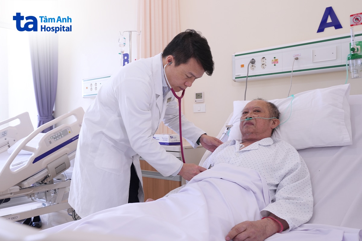 Bác sĩ dùng ống nghe thăm khám người bệnh nằm trên giường bệnh
