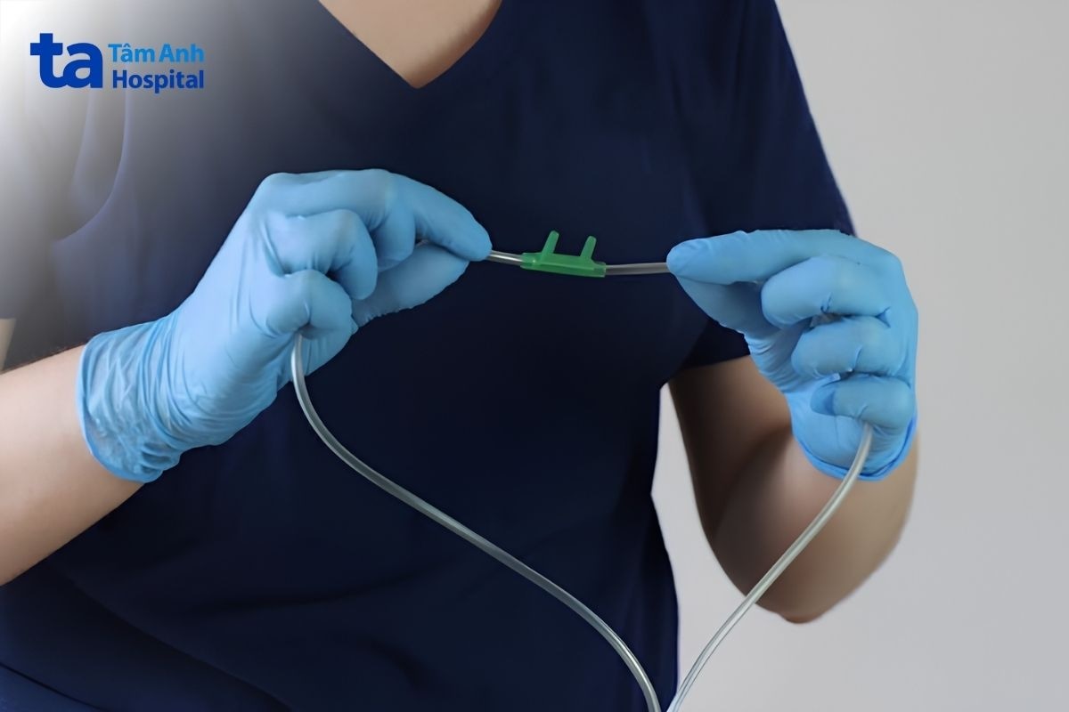 Điều dưỡng đeo găng tay cầm ống cannula có hai nhánh mũi