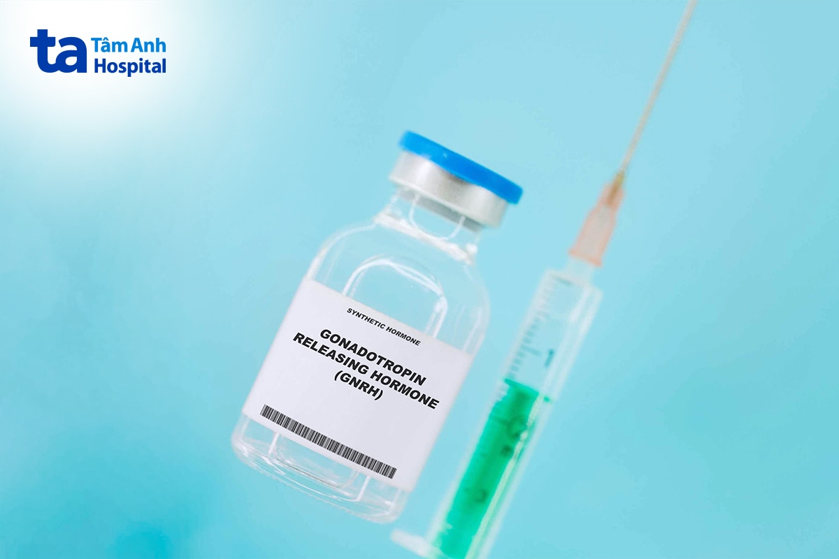 Lọ thuốc hormone GnRH tổng hợp đặt cạnh bơm tiêm trên nền xanh