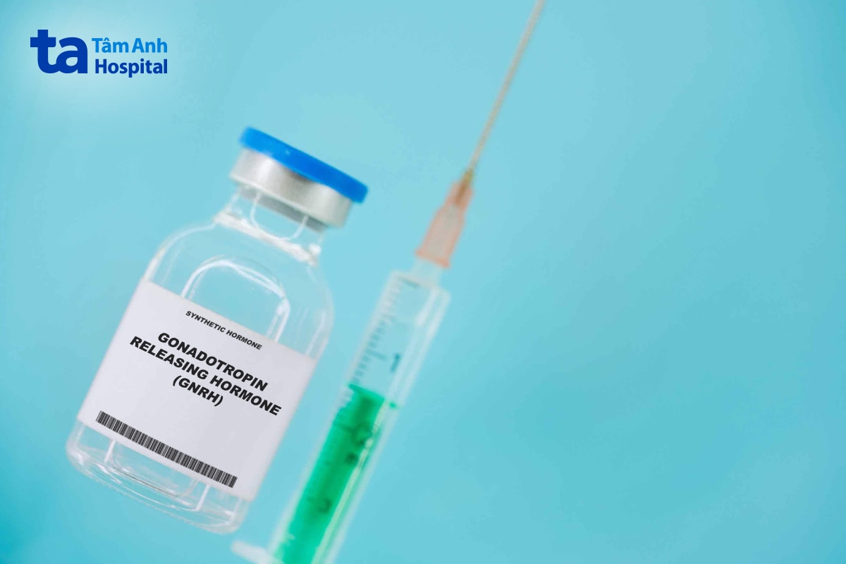 Lọ thuốc hormone GnRH tổng hợp đặt cạnh bơm tiêm trên nền xanh