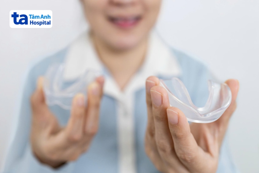 Người bệnh cầm trên tay hai máng nhai trong suốt dùng cho hàm