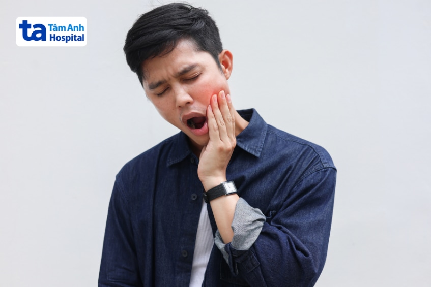 Người nam ôm má, nhăn mặt vì đau hàm và há miệng khó khép lại